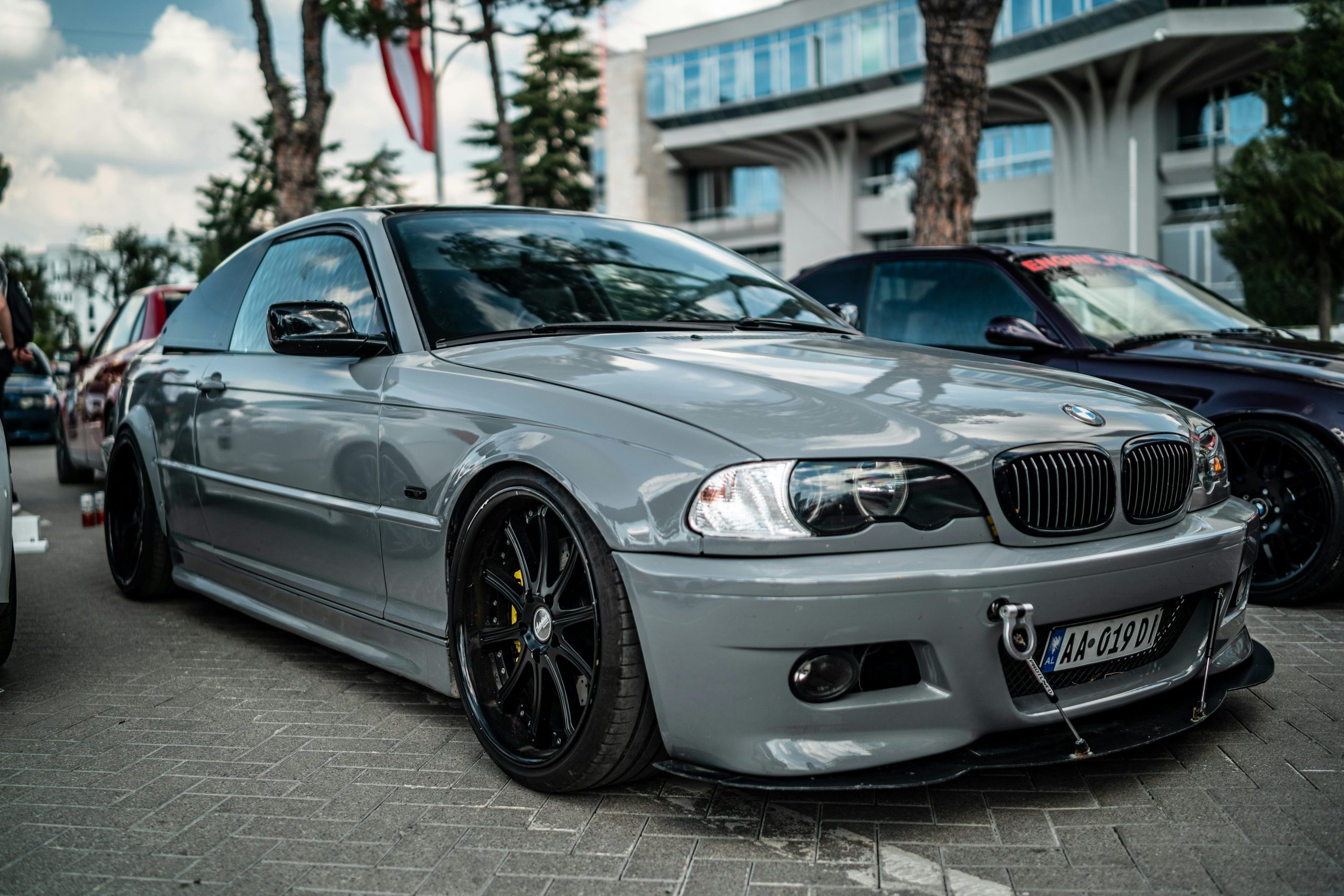 A sleek grey BMW E46 showcased at an outdoor car event, highlighting its sporty design.